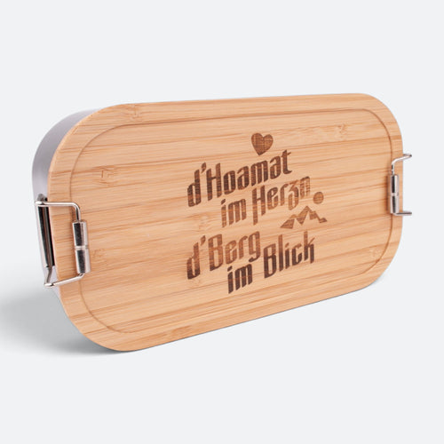 Brotzeitbox mit Bambusdeckel und der Gravur „d'Hoamat im Herzn, d'Berg im Blick“ mit Herz und Bergen.
