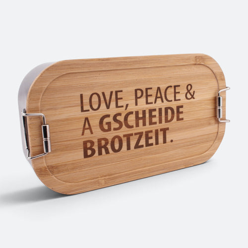 Brotzeitbox mit Bambusdeckel und der Gravur „Love, Peace & a gscheide Brotzeit.“.