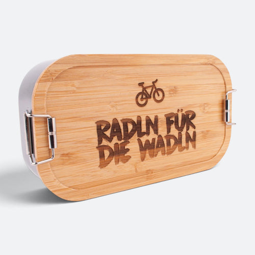 Brotzeitbox mit Bambusdeckel, eingraviertem Fahrrad und dem Spruch „Radln für die Wadln“.