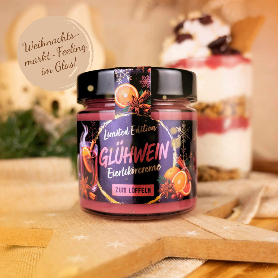 Glas Eierlikörcreme Glühwein zum Löffeln, Limited Edition, auf einem Holzstern vor einem Dessertglas mit Beeren