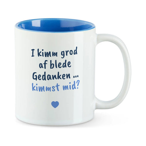 Weiße Tasse mit blauer Innenseite und dem bairischen Spruch „I kimm grod af blede Gedanken … kimmst mid?“ in Pinselschrift.