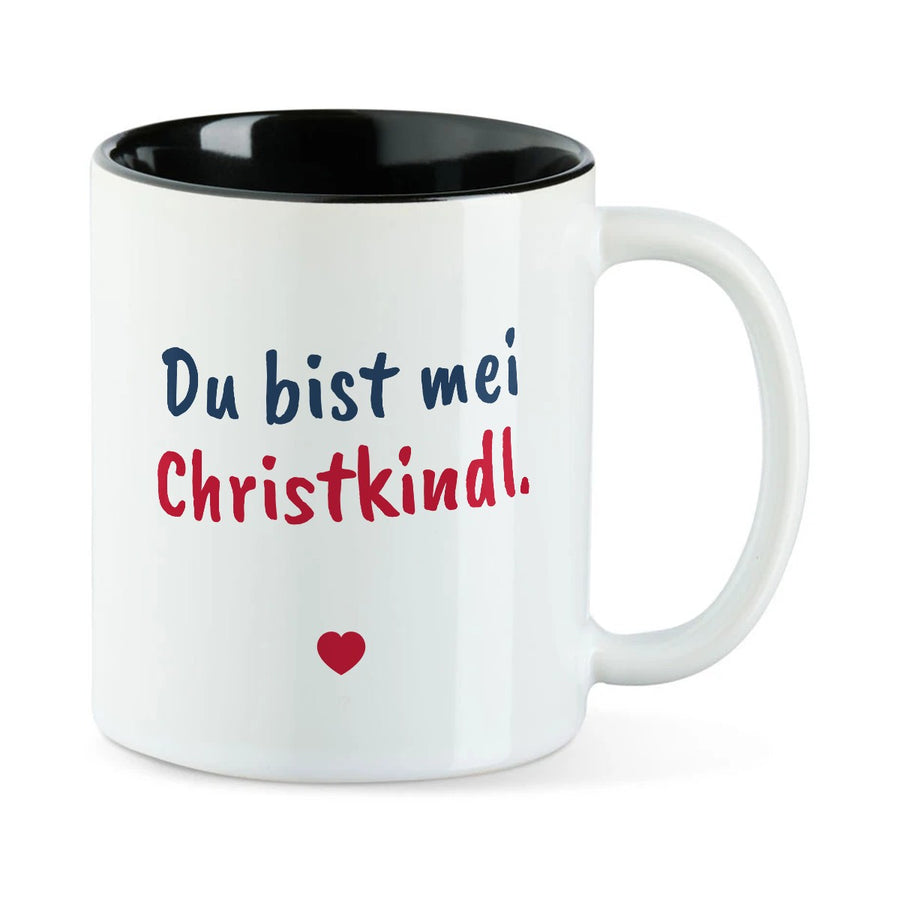 Weiße Tasse mit schwarzer Innenseite und dem bairischen Spruch „Du bist mei Christkindl.“ in Pinselschrift.