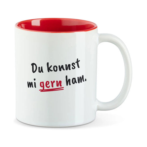 Weiße Tasse mit roter Innenseite und dem bairischen Spruch „Du konnst mi gern ham.“ in Pinselschrift.