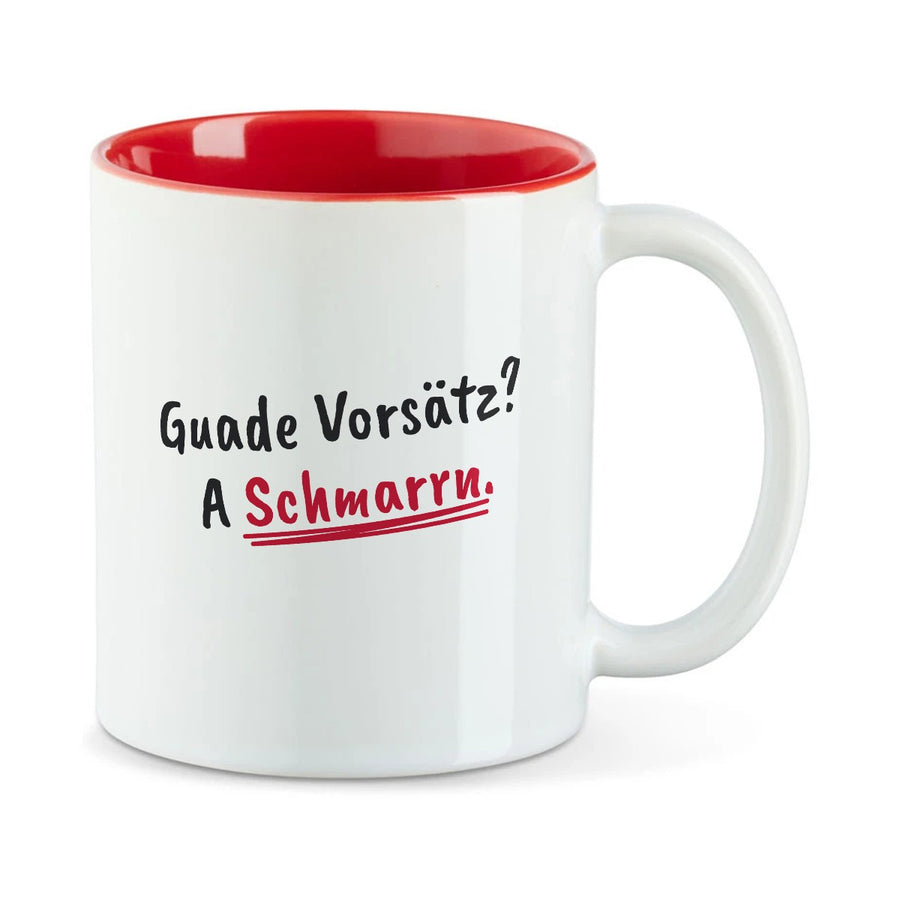 Weiße Tasse mit roter Innenseite und dem bairischen Spruch „Guade Vorsätz? A Schmarrn.“ in Pinselschrift.