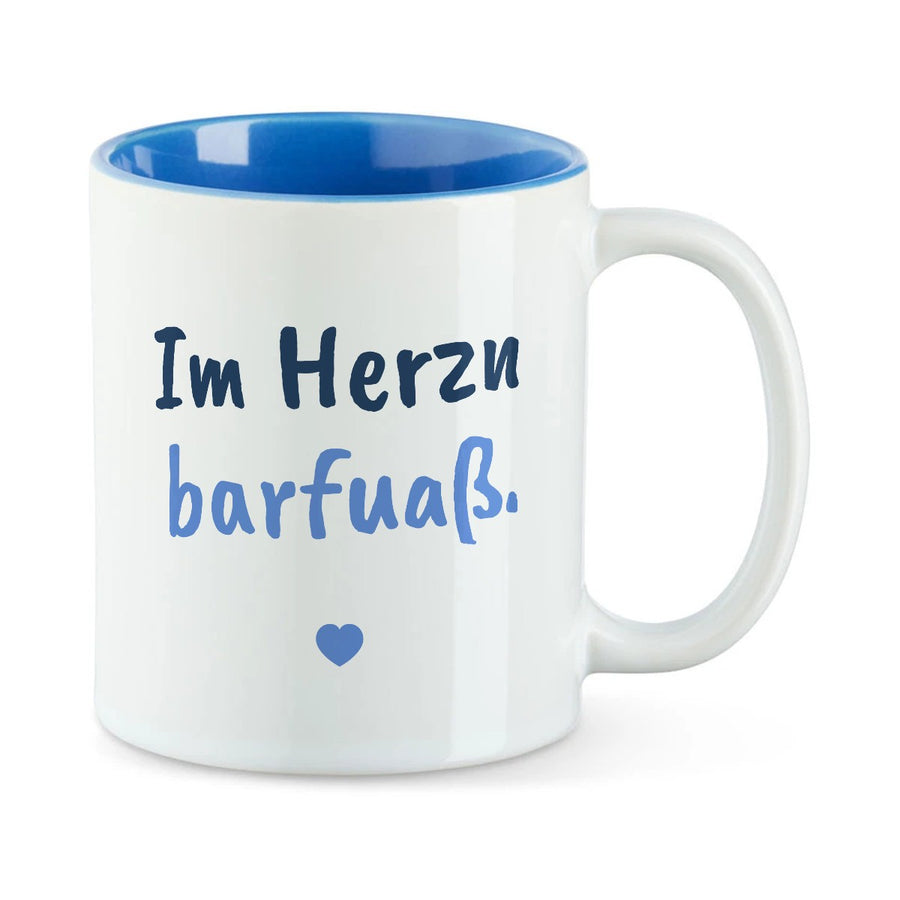 Weiße Tasse mit blauer Innenseite und dem bairischen Spruch „Im Herzn barfuaß.“ in Pinselschrift.