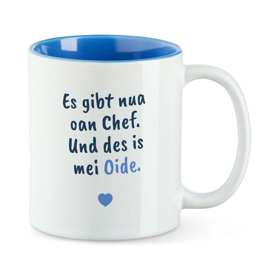 Weiße Tasse mit blauer Innenseite und dem bairischen Spruch „Es gibt nua oan Chef. Und des is mei Oide.“ in Pinselschrift.