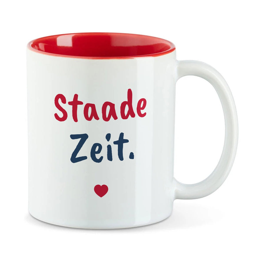 Weiße Tasse mit roter Innenseite und dem bairischen Spruch „Staade Zeit.“ in Pinselschrift.
