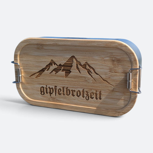 Brotzeitbox aus Edelstahl mit Bambusdeckel, eingravierter Bergkette und dem Schriftzug „gipfelbrotzeit“.