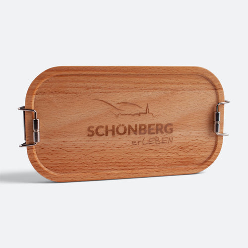 Brotzeitbox mit Buchenholzdeckel als Beispiel für eine Wunschgravur: eingraviertes Logo „Schönberg erLEBEN“ mit Ortsansicht.