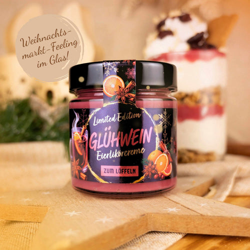 Glas Eierlikörcreme Glühwein zum Löffeln, Limited Edition, auf einem Holzstern vor einem Dessertglas mit Beeren