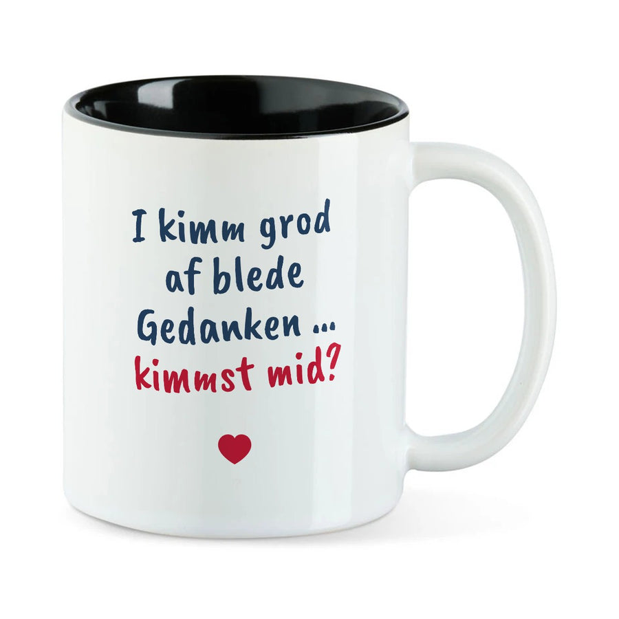 Weiße Tasse mit schwarzer Innenseite und dem bairischen Spruch „I kimm grod af blede Gedanken … kimmst mid?“ in Pinselschrift.