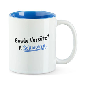 Weiße Tasse mit blauer Innenseite und dem bairischen Spruch „Guade Vorsätz? A Schmarrn.“ in Pinselschrift.