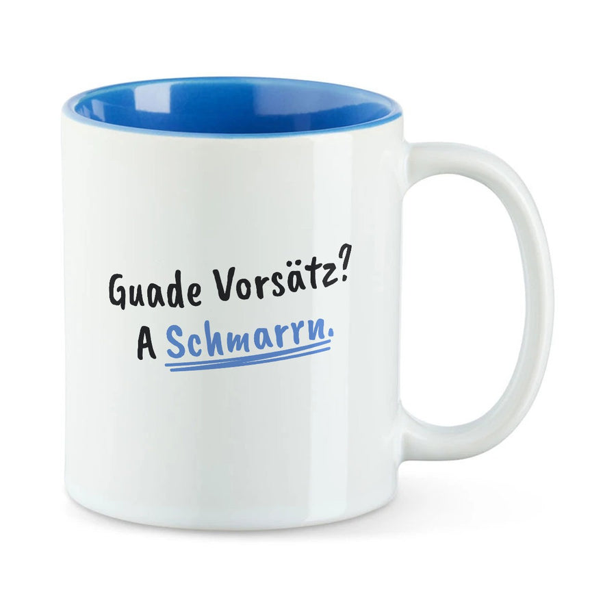 Weiße Tasse mit blauer Innenseite und dem bairischen Spruch „Guade Vorsätz? A Schmarrn.“ in Pinselschrift.
