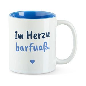 Weiße Tasse mit blauer Innenseite und dem bairischen Spruch „Im Herzn barfuaß.“ in Pinselschrift.