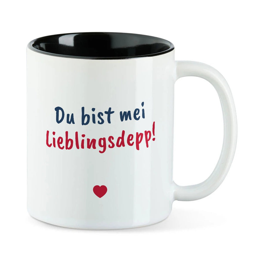Weiße Tasse mit schwarzer Innenseite und dem bairischen Spruch „Du bist mei Lieblingsdepp!“ in Pinselschrift.