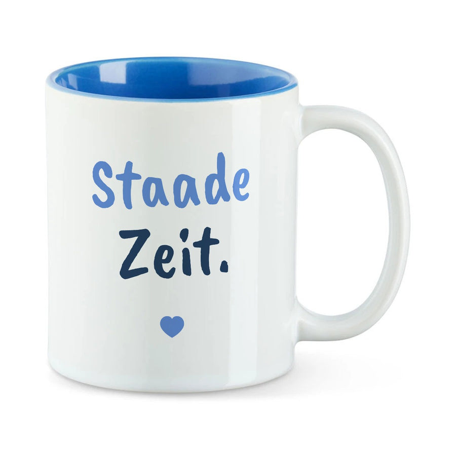 Weiße Tasse mit blauer Innenseite und dem bairischen Spruch „Staade Zeit.“ in Pinselschrift.