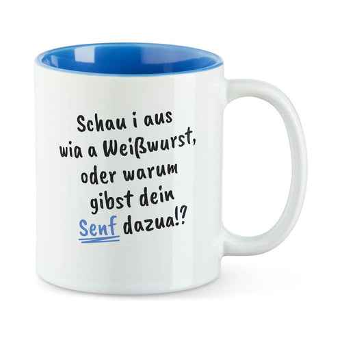 Weiße Tasse mit blauer Innenseite und dem bairischen Spruch „Schau i aus wia a Weißwurst, oder warum gibst dein Senf dazua!?“ in Pinselschrift.